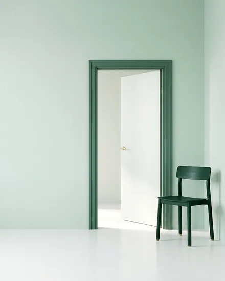 Sala clara em tom menta com uma porta aberta e uma cadeira verde ao lado.